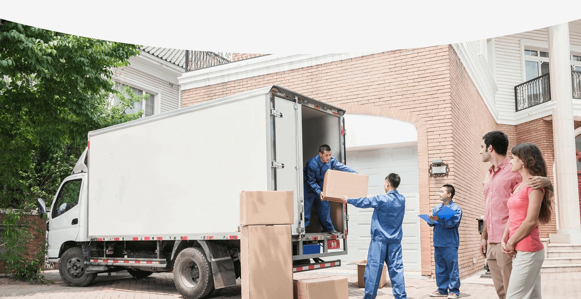 Young Couple Watching Movers Move Boxes From the Moving Van