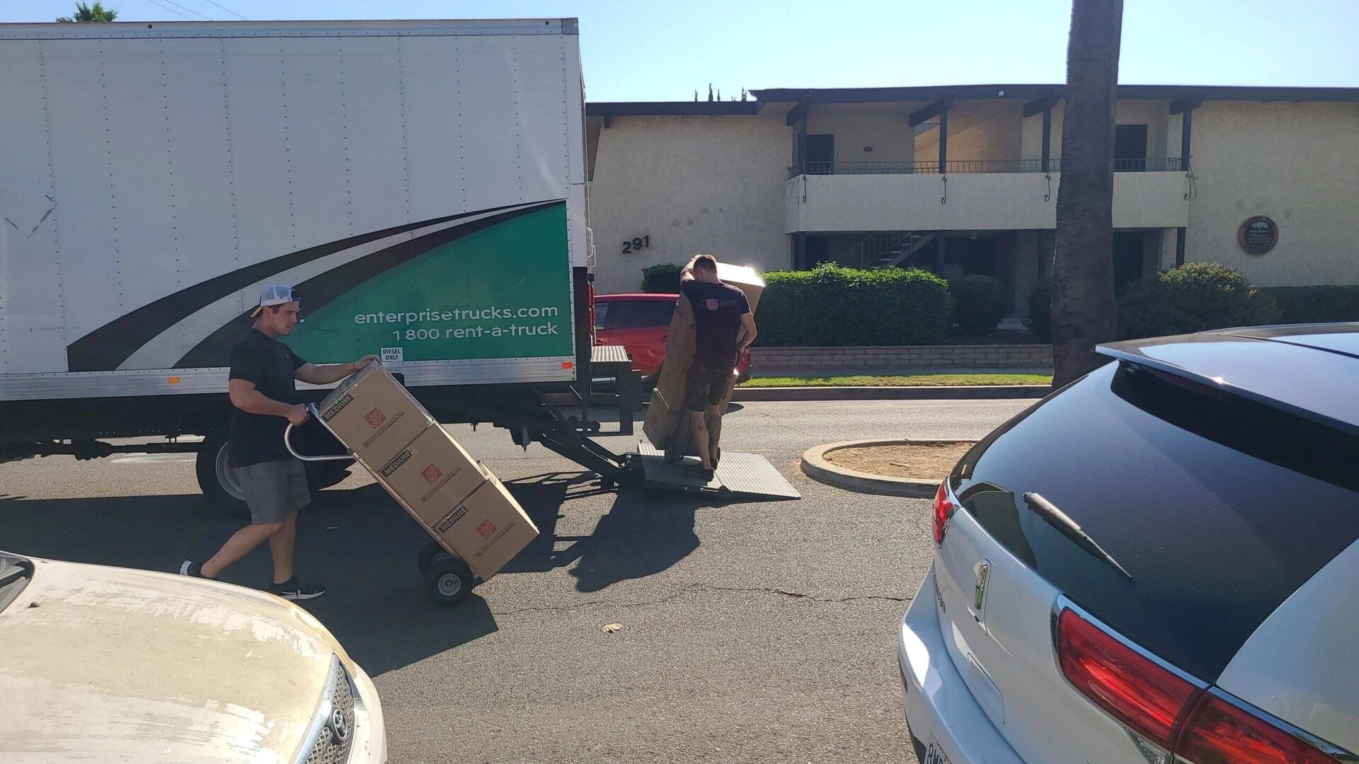 Delivery Man Loading Cardboard Boxes Into the Truck With His Colleague