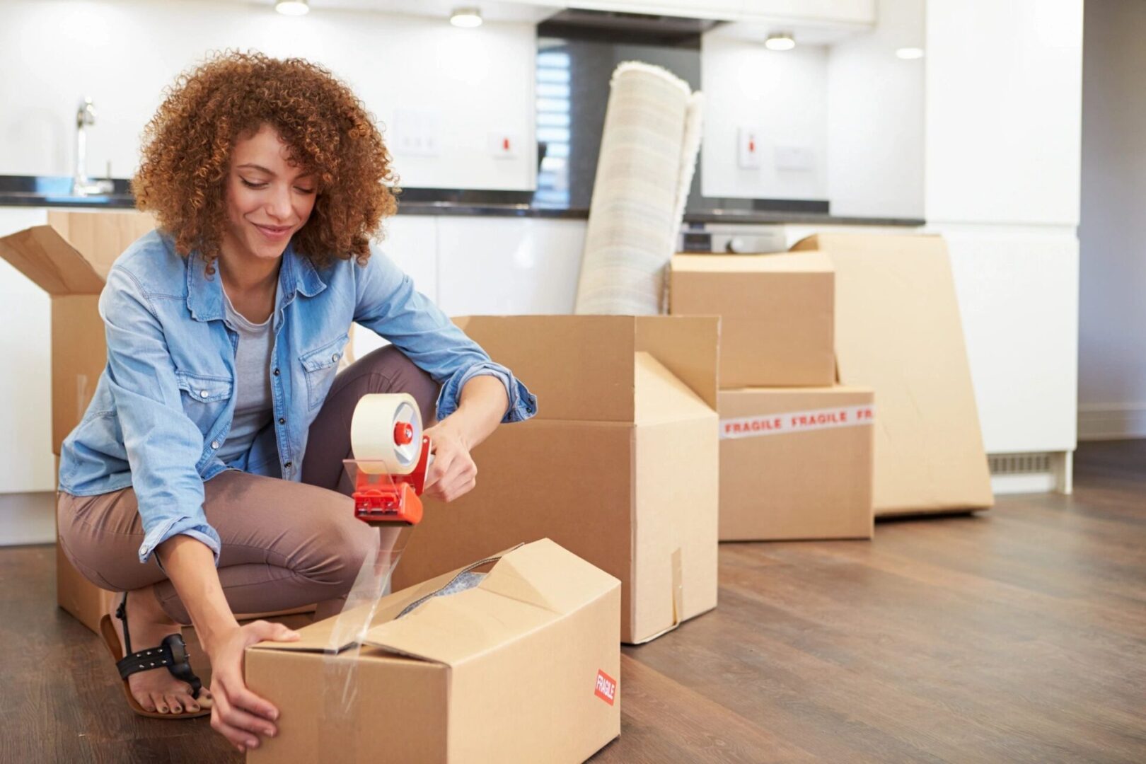 Woman Kneeling Down Sealing Boxes Ready for House Move