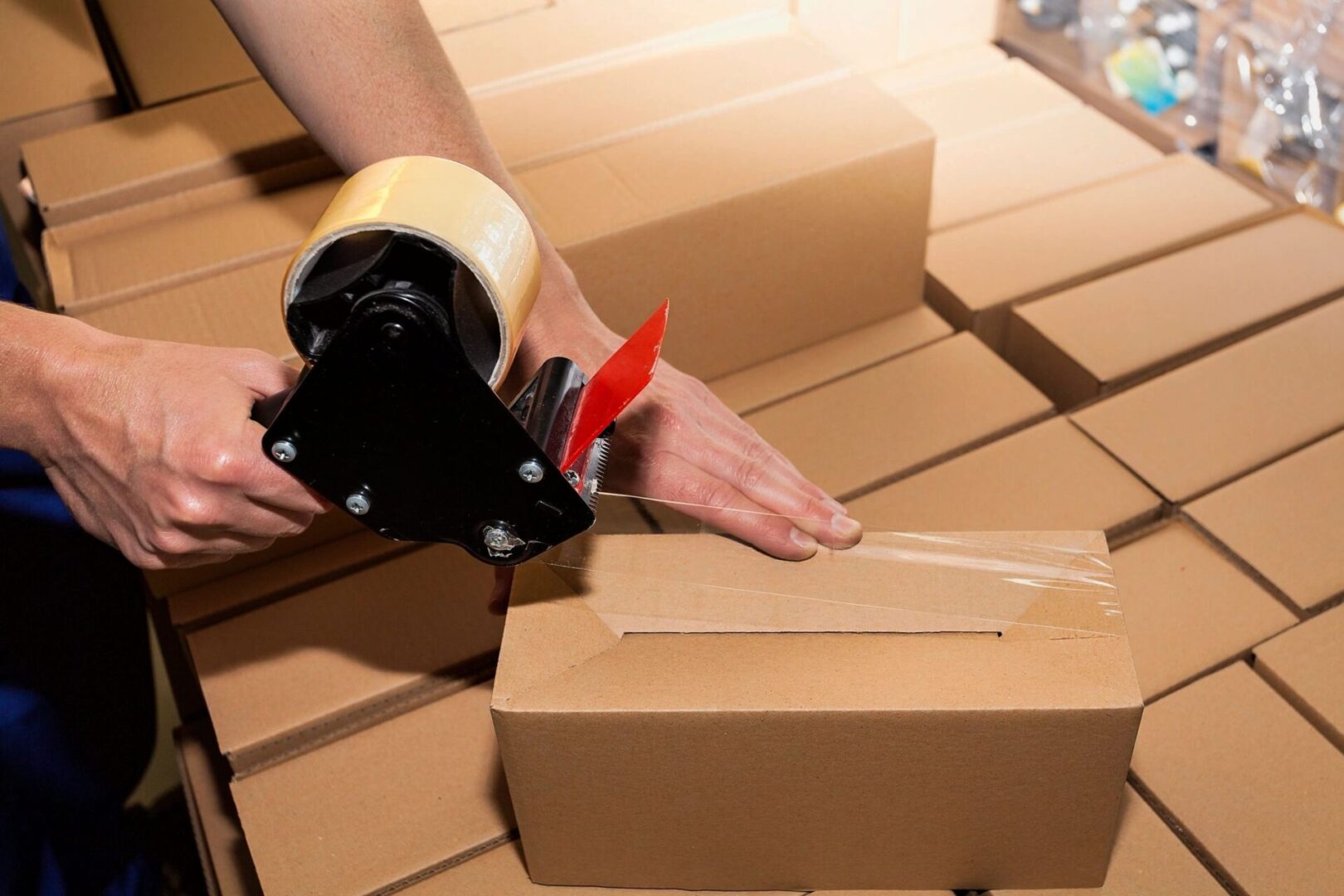 Close Up of a Guy's Hands Holding Packing Machine and Sealing Cardboard Boxes With Duct Tape