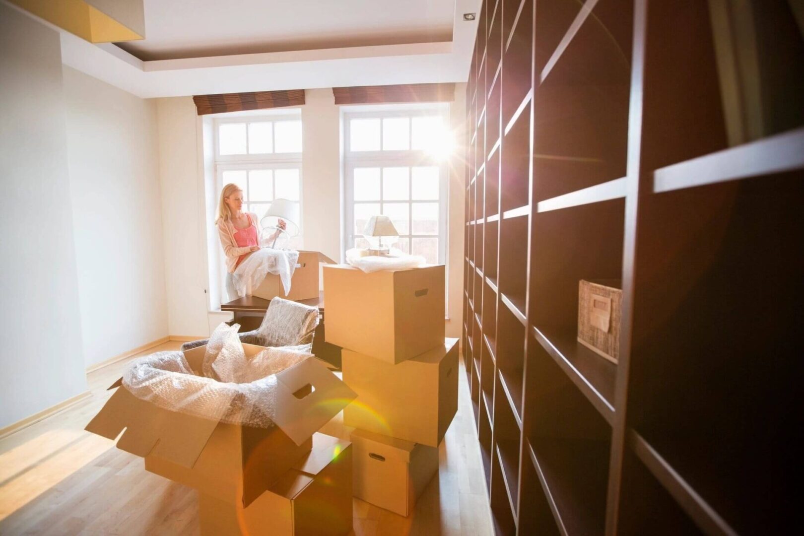 Woman Unpacking Lamp From Moving Box at New House