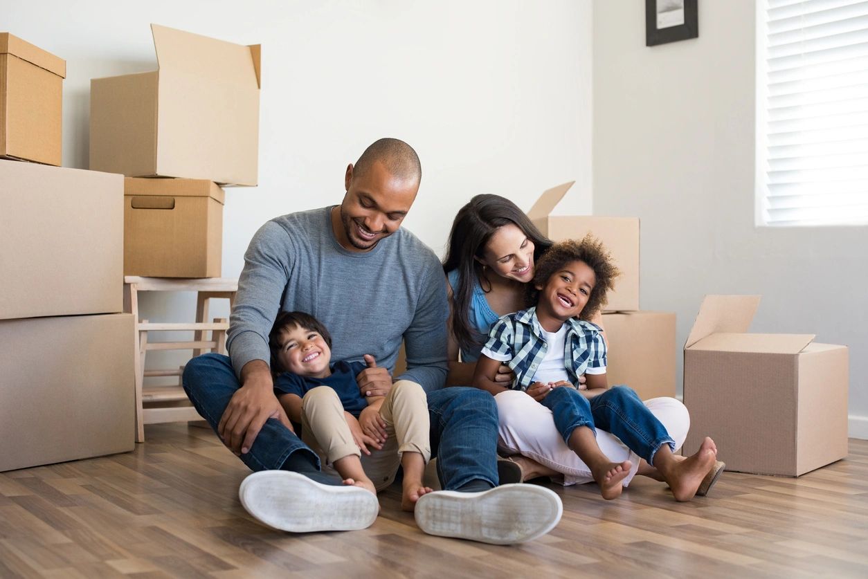 Happy Family Sitting on the Floor Smiling at a New House Moving.