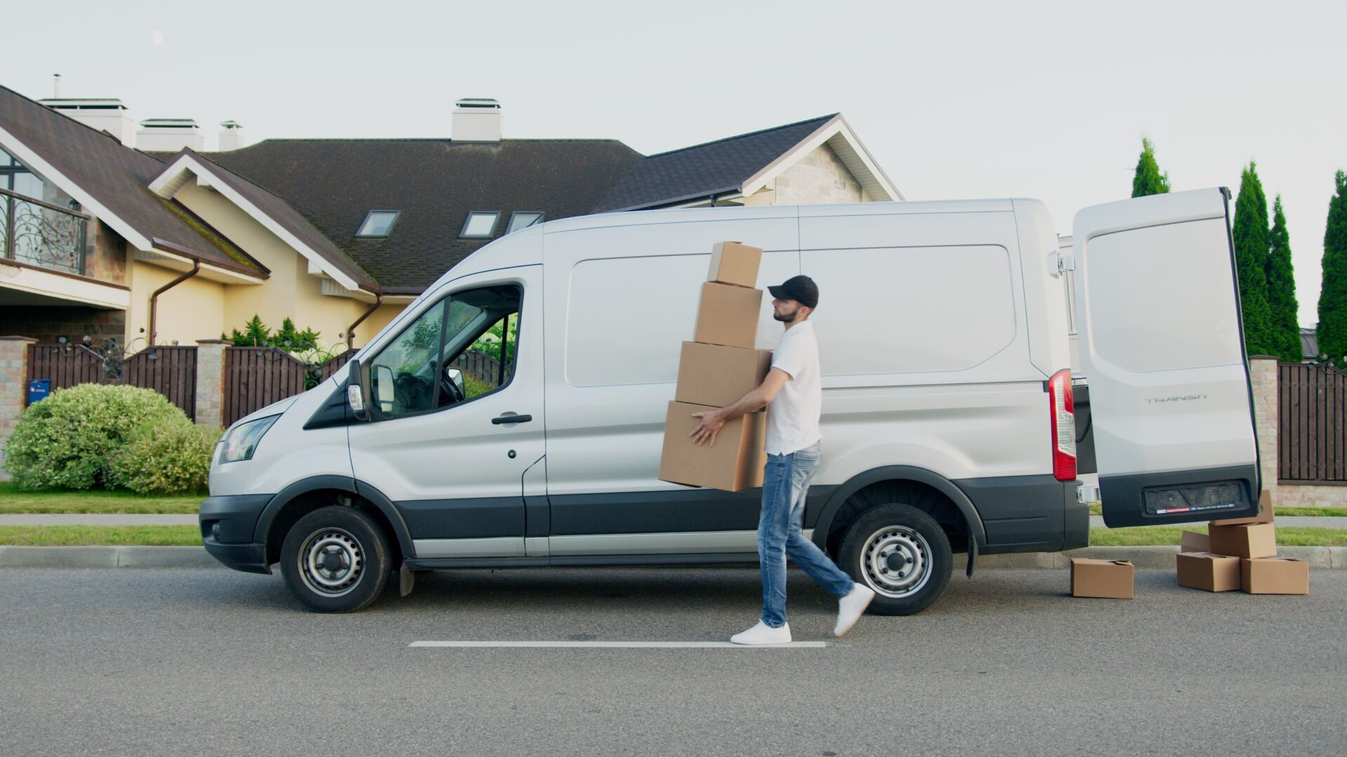 Young Delivery Man Unloading Boxes From a Mini Van.